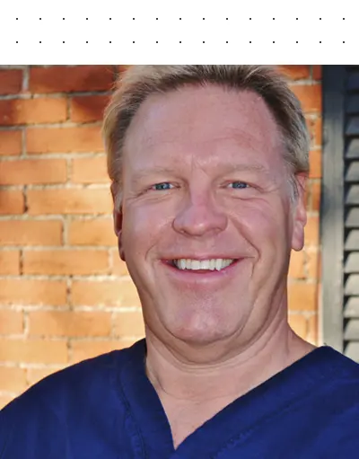 A man with blonde hair and blue shirt smiling.