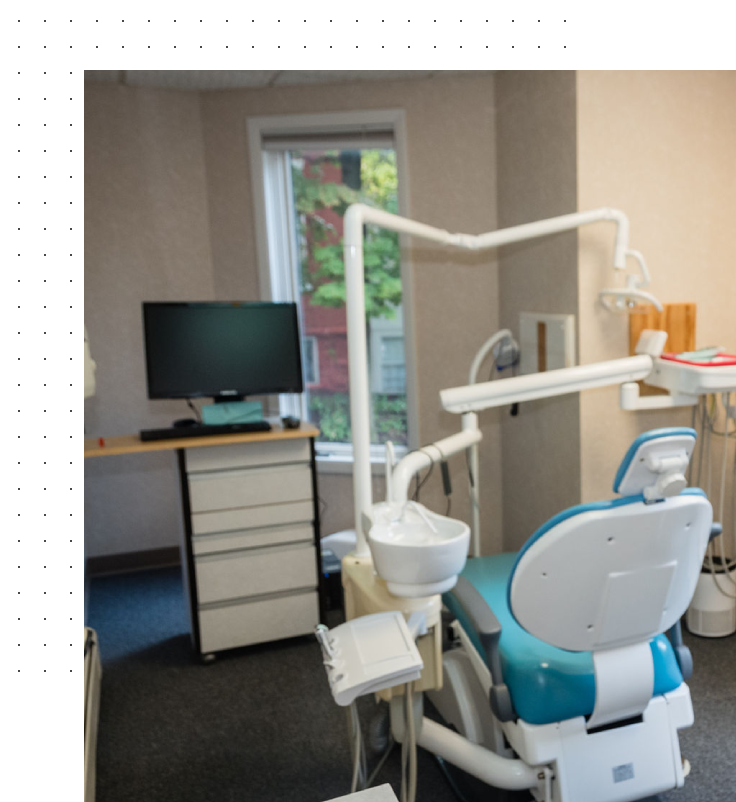 A dentist 's office with a chair and television.